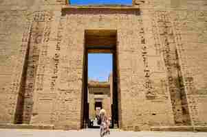 Foto gratuita primo piano di una donna in piedi di fronte a un tempio di medinet habu in egitto