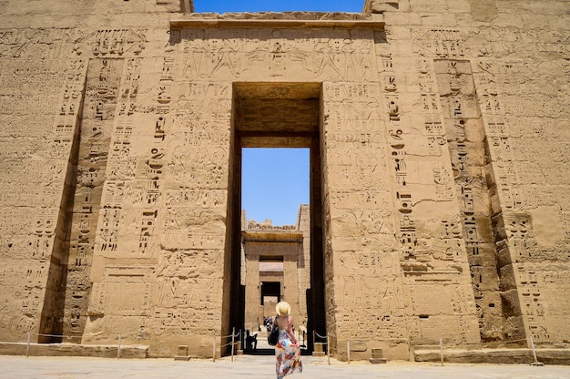 Closeup shot of a female standing in front of a Medinet Habu temple in Egypt