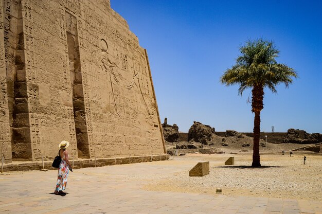 Closeup shot of a female standing in front of a Medinet Habu temple in Egypt