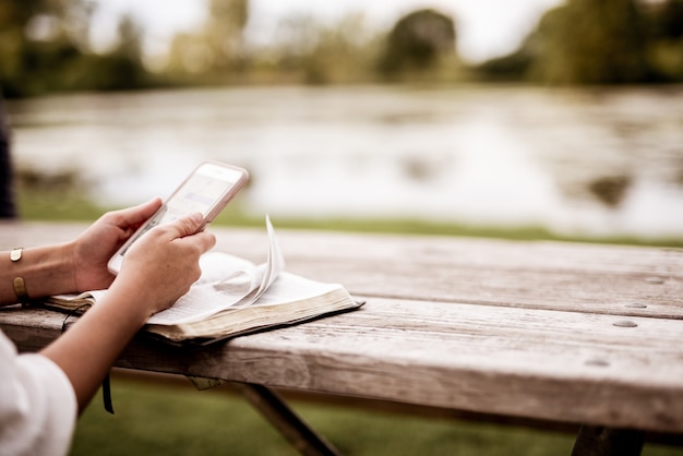 Free photo closeup shot of a female using her smartphone with the bible