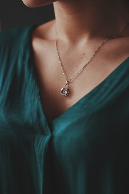 ダイヤモンドのペンダントと美しい銀のネックレスを身に着けている女性のクローズアップショット