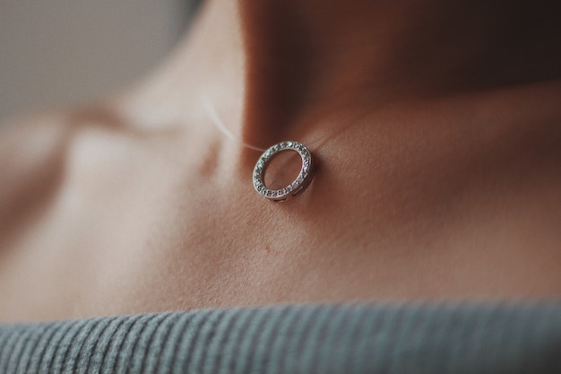 Closeup shot of a female wearing a beautiful silver necklace with a pendant