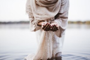 Il colpo del primo piano di una femmina che indossa un abito biblico che tiene l'acqua con le sue palme