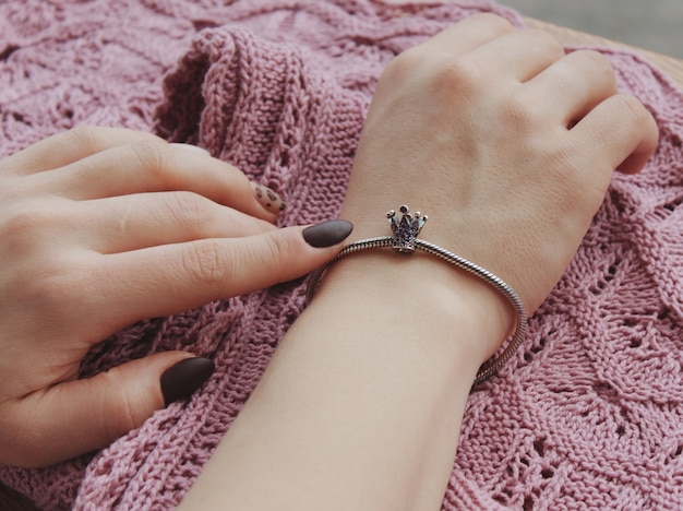 Closeup shot of a female wearing a fashionable bracelet with charm pendants