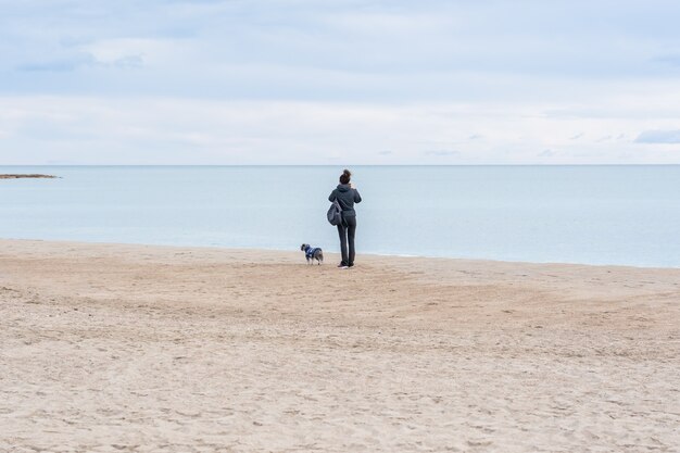 ビーチに立って美しい景色を観察している彼女の犬と女性のクローズアップショット