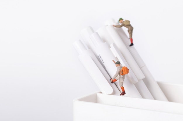 Closeup shot of figurines of students climbing on pens in a pot