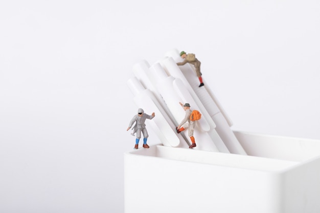 Closeup shot of figurines of students climbing on pens in a pot