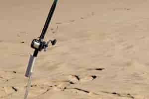 Free photo closeup shot of a fishing pole in a sandy surface