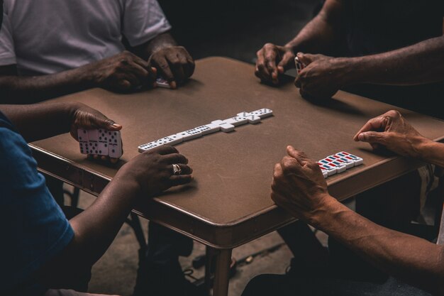 Closeup shot of four African people playing dominoes around a table