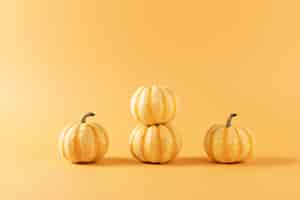 Free photo closeup shot of four pumpkins isolated on orange background