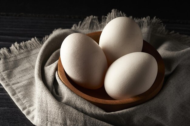 Closeup shot of fresh eggs a wooden bowl and a tablecloth