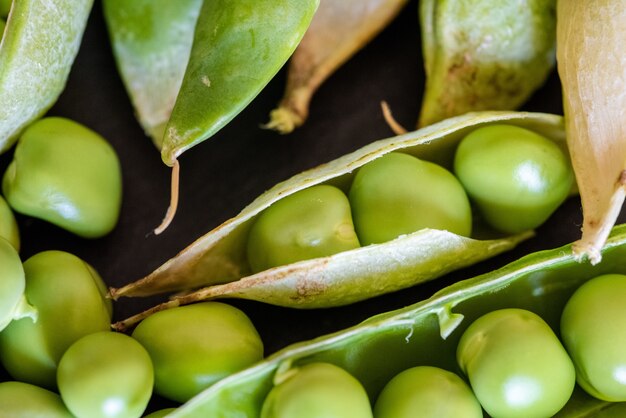 Closeup shot of fresh green pea seeds on black wooden background