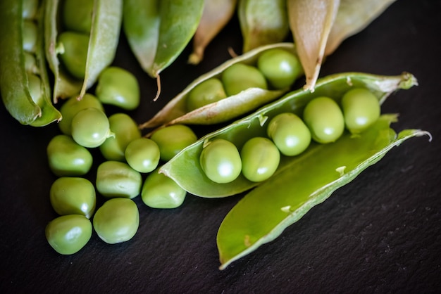 Closeup shot of fresh green pea seeds on black wooden background