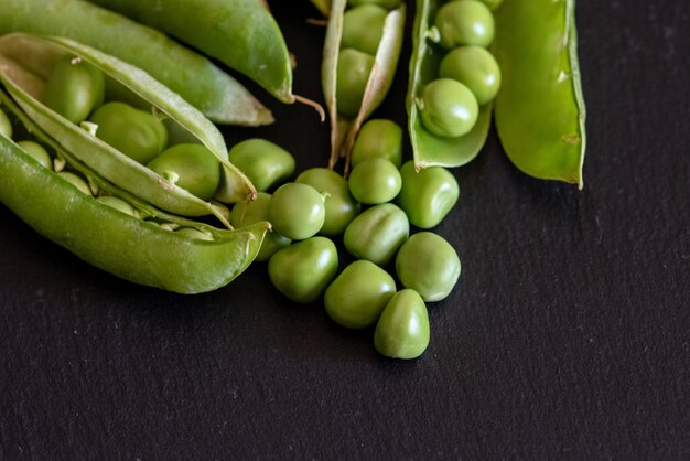 Closeup shot of fresh green pea seeds on black wooden table