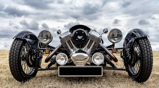 Closeup shot of the front of a black vehicle parked on a dry field under a cloudy sky