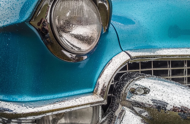 Closeup shot of the front part of a blue car including the lights and the bumper