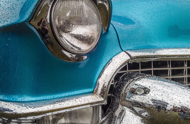 Closeup shot of the front part of a blue car including the lights and the bumper