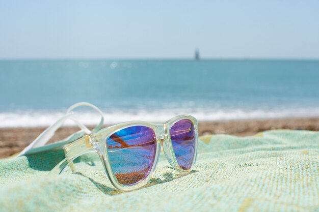 Closeup shot of funky sunglasses on the beach towel on a sand beach