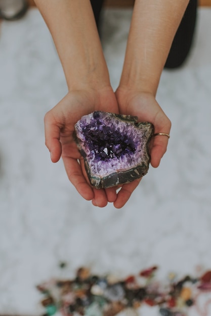 Closeup shot of a girl holding a multicolored rock in her hands over a white surface