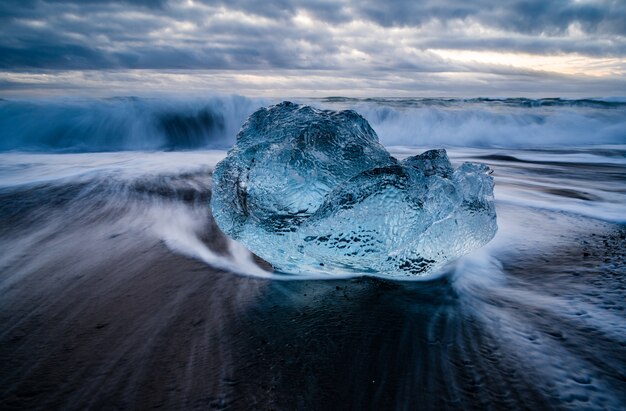 Closeup shot of a glacier lagoon in Iceland with a wavy sea on the background