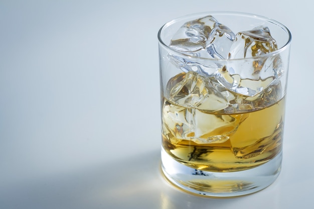 氷と白い背景で隔離のウイスキーでいっぱいのガラスのクローズアップショット