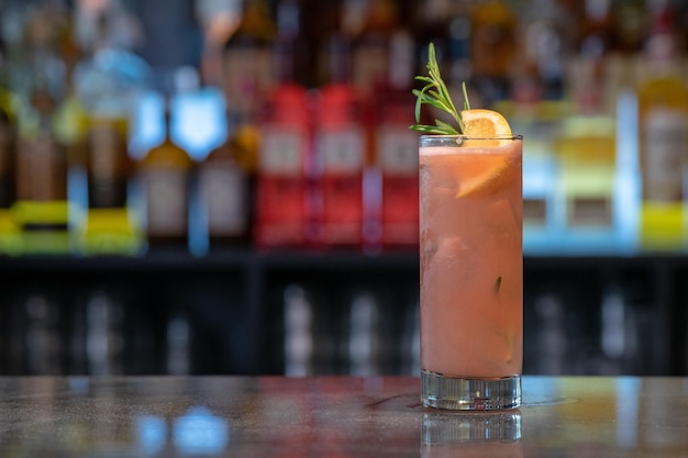 Closeup shot of a glass of iced cocktail with orange on a bar counter