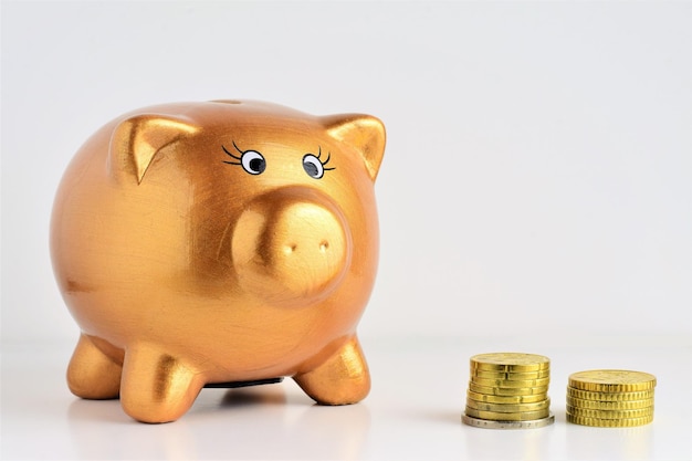 Free photo closeup shot of a golden pig cashbox and coins on a white background