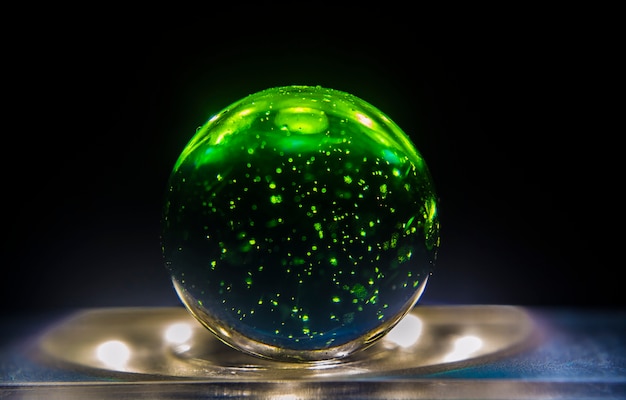 Closeup shot of a green marble on top of a lit surface