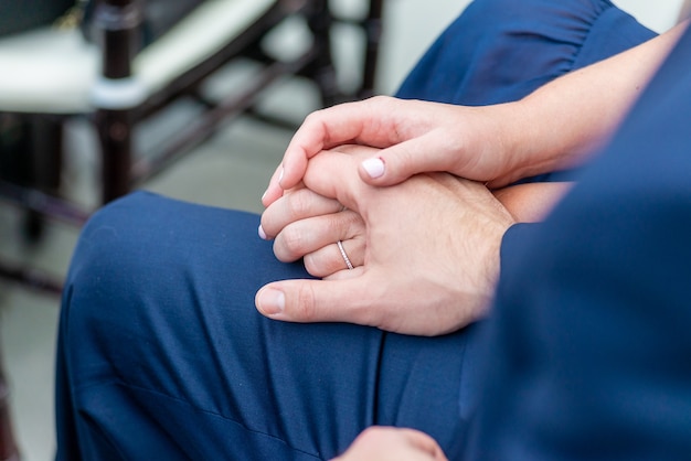 Foto gratuita colpo del primo piano dello sposo e della sposa seduti, le mani poste una sopra l'altra