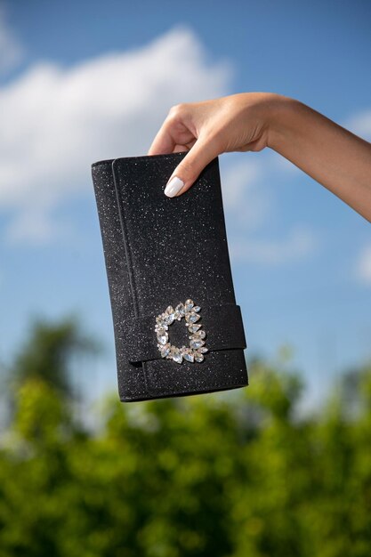 Closeup shot of a hand holding a luxurious black purse