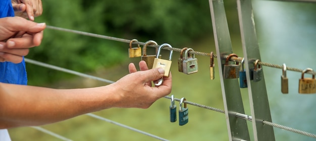 Foto gratuita colpo del primo piano delle mani che appendono le serrature su una corda - concetto di amore