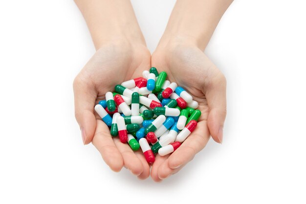 Closeup shot of hands holding a bunch of colorful capsules