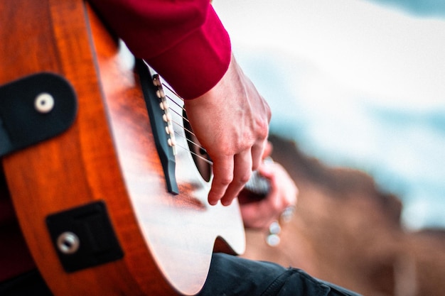 Foto gratuita colpo del primo piano delle mani che suonano la chitarra acustica