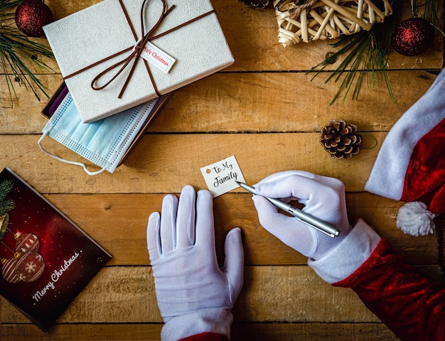 Closeup shot of hands in white gloves writing "To my family" on a card for a present and a mask