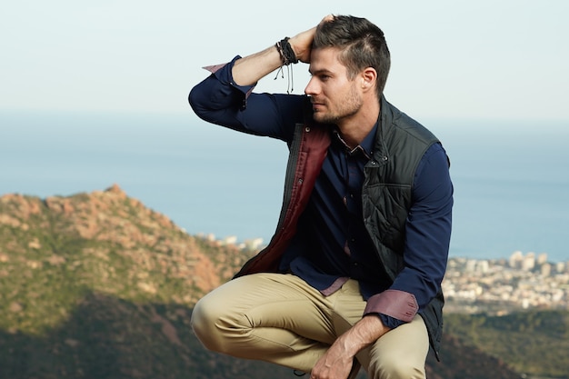 Closeup shot of a handsome male touching his hair in squatting sitting position