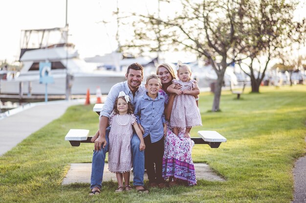 Снимок крупным планом счастливой семьи, стоящей на траве возле гавани - концепция семьи