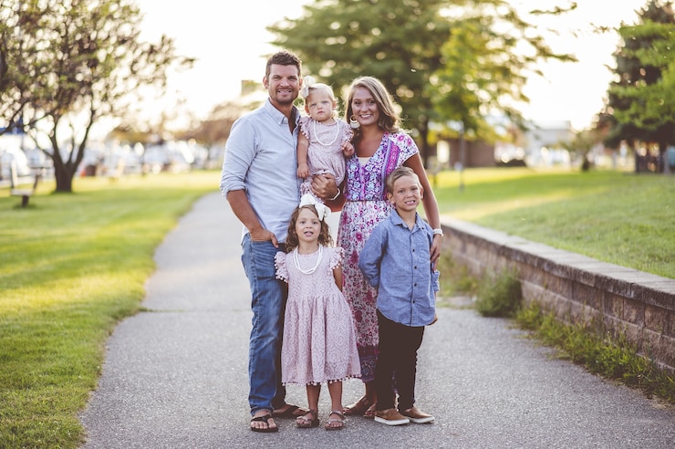 Free Photo closeup shot of a happy family standing on the grass near the harbor - family concept