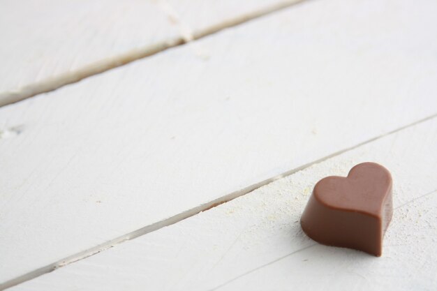 Closeup shot of a heart-shaped chocolate candy on a white wooden table