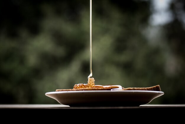 Closeup shot of honey pouring on the bread slices on a plate