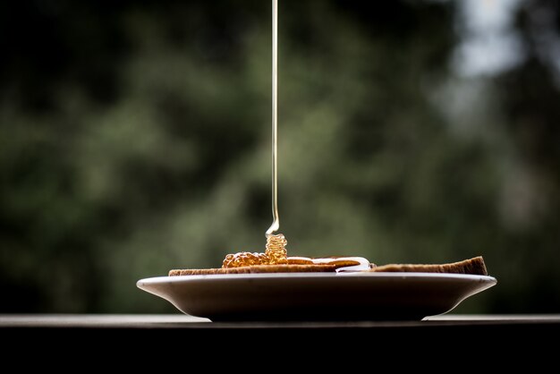 접시에 빵 조각에 붓는 꿀의 근접 촬영 샷