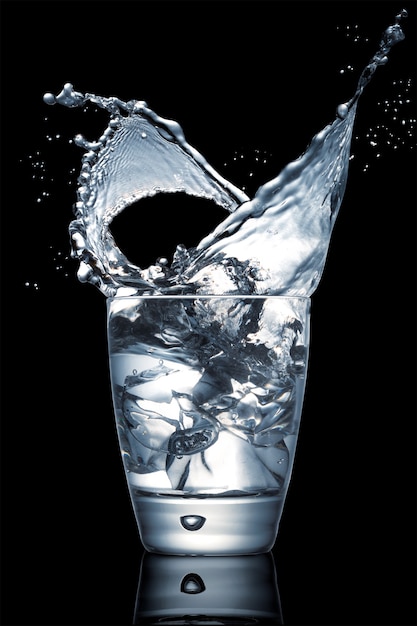 Closeup shot of an impressive water splash in a glass cup on a black background