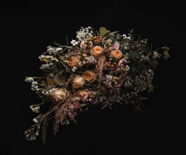 Closeup shot of a luxurious bouquet of orange and brown roses on a black background