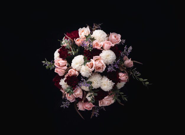 Closeup shot of a luxurious bouquet of pink roses and white, red dahlias on a black background