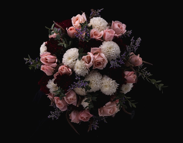 Closeup shot of a luxurious bouquet of pink roses and white, red dahlias on a black background