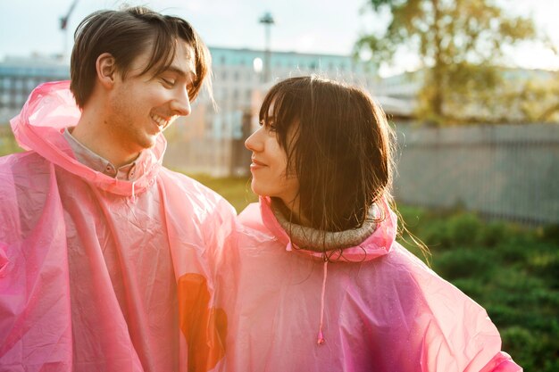 ロマンチックにお互いを見てピンクのプラスチック製のレインコートを着た男性と女性のクローズアップショット