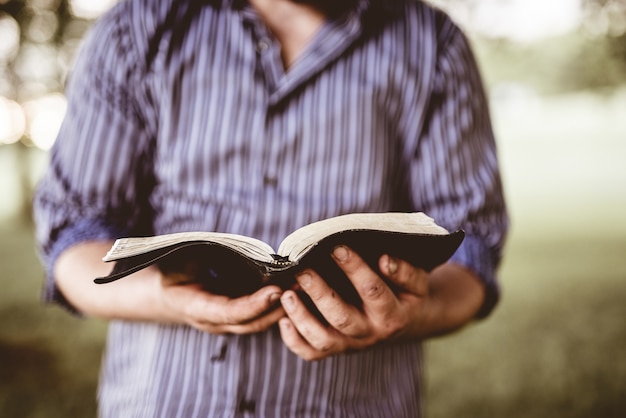 Free photo closeup shot of a male holding an open bible with a blurred background