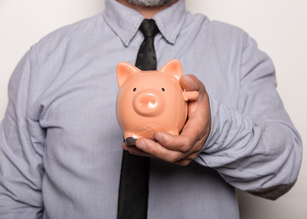 Closeup shot of a male holding a piggy bank