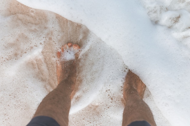 海の水で男性の足のクローズアップショット