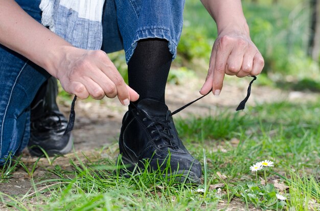 잔디 덮인 필드에 그의 신발 끈을 묶는 남성 손의 근접 촬영 샷