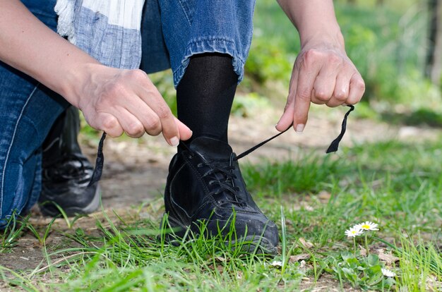 草で覆われたフィールドで彼の靴ひもを結ぶ男性の手のクローズアップショット